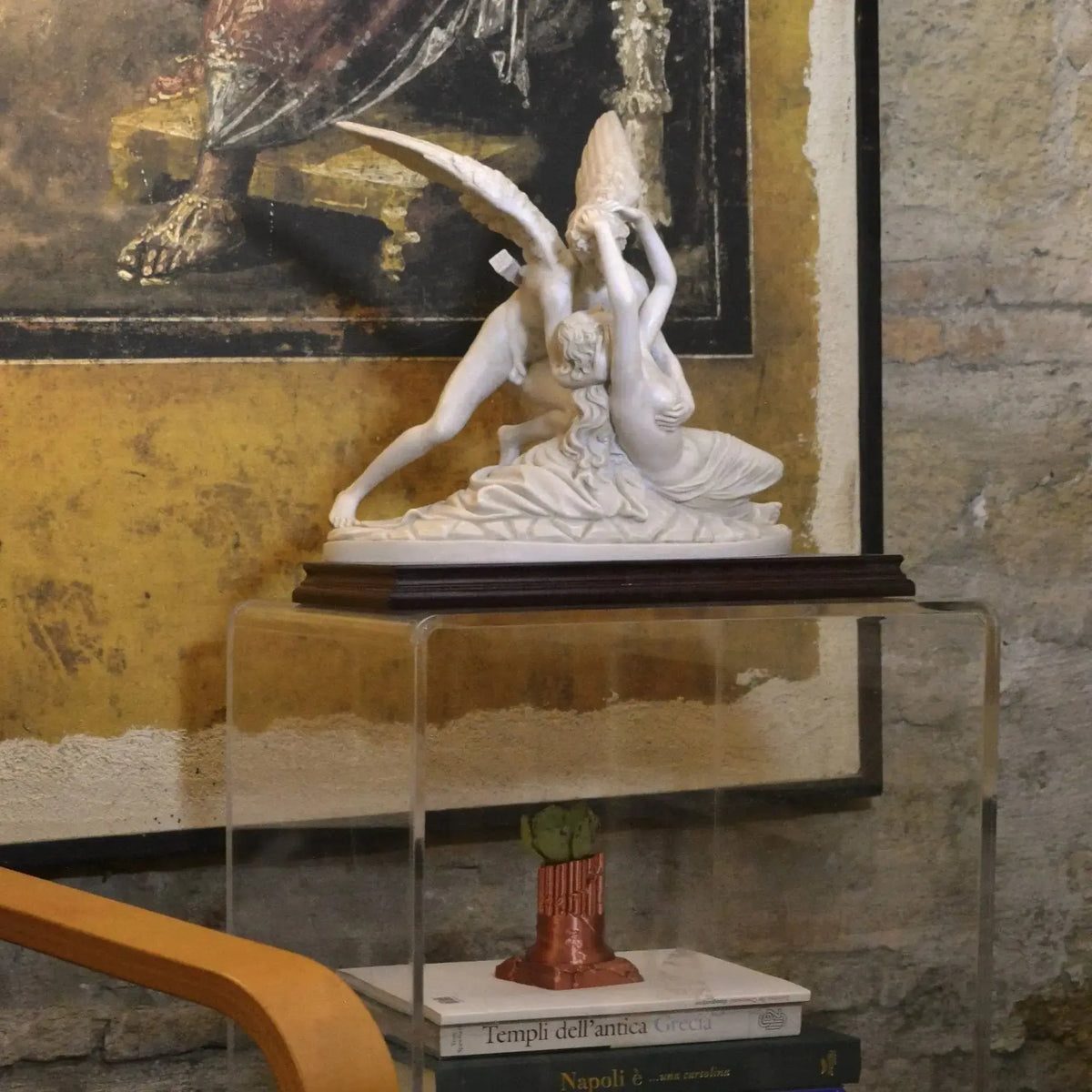 Amore e Psiche in marmo ricomposto su base in legno, su un supporto trasparente davanti a un quadro