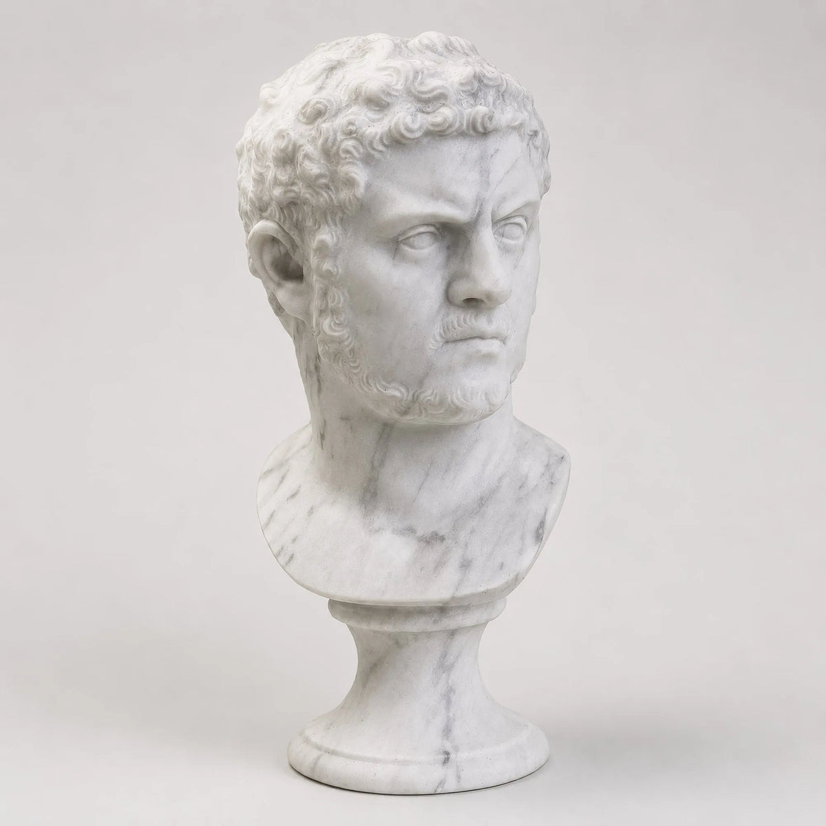 Busto di Caracalla in marmo di Carrara, vista frontale su fondo grigio chiaro.
