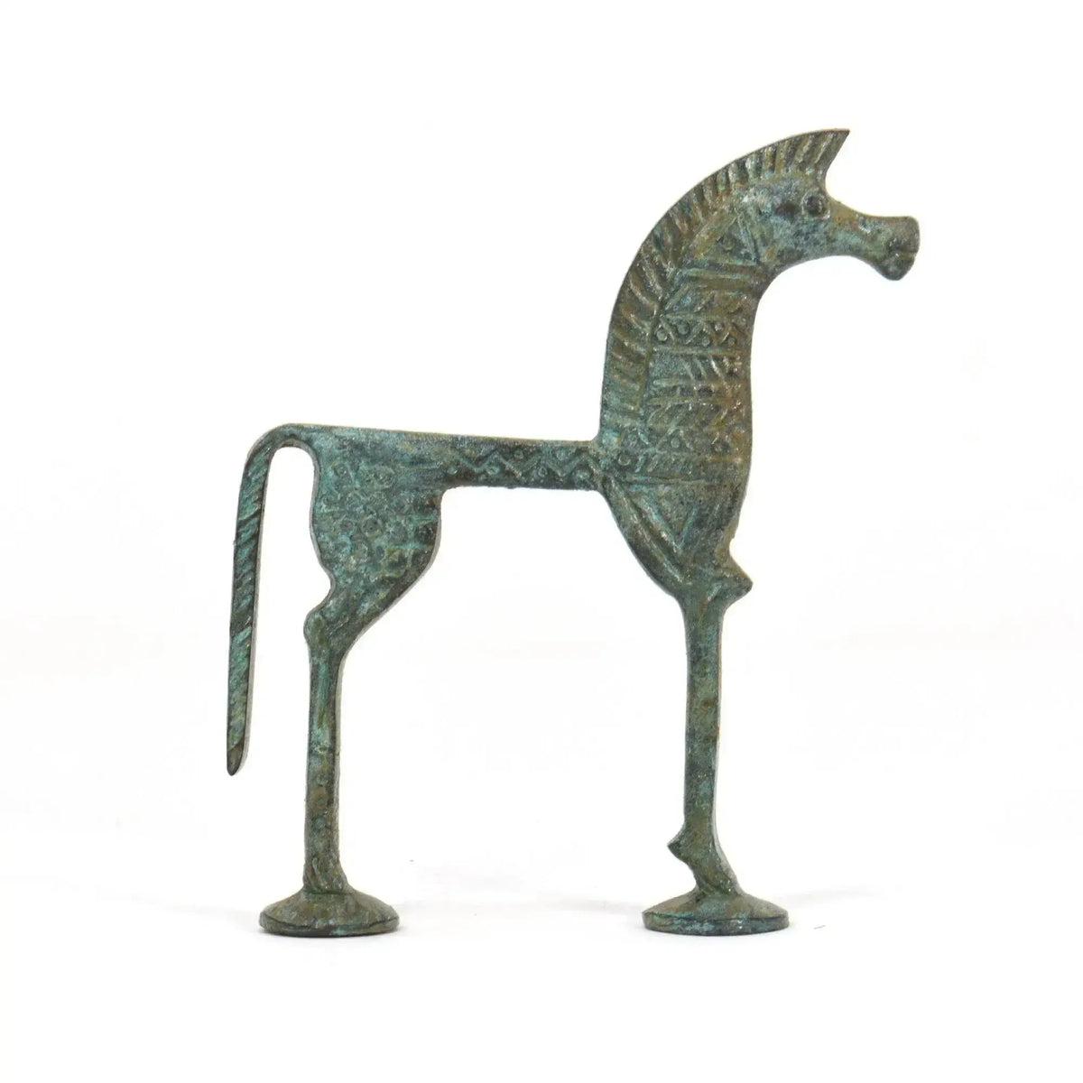 Statuetta in bronzo di cavallo greco con patina verde, corpo stilizzato e decorazioni in rilievo, fotografata di profilo su fondo bianco.