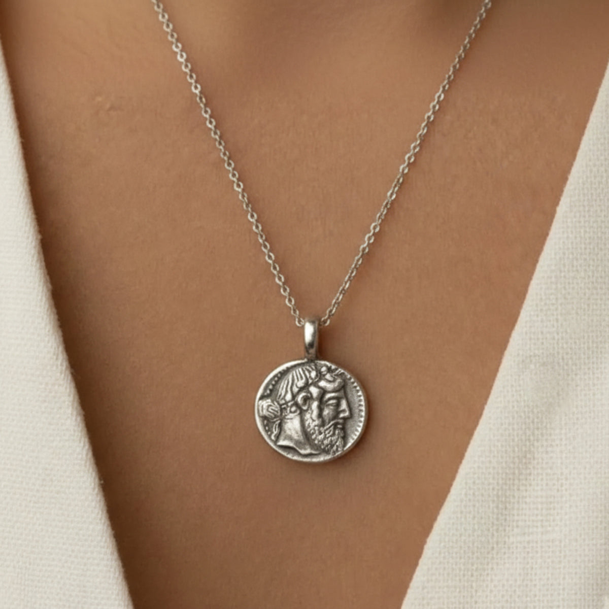 Ciondolo in argento con riproduzione della moneta di Naxos e profilo di Dioniso, indossato con un capo bianco