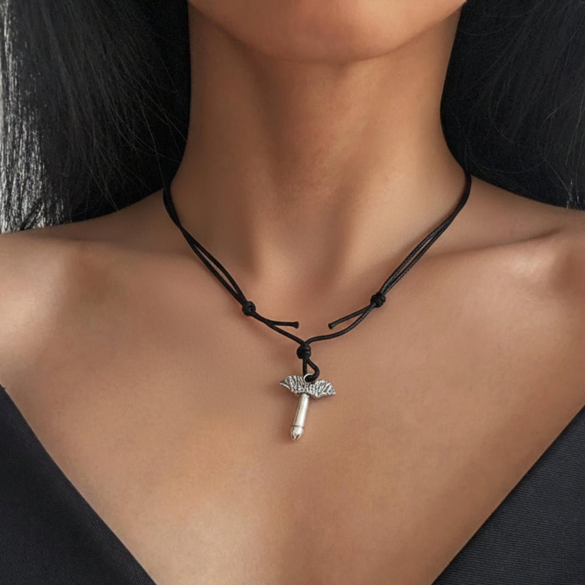 Collana con fallo alato in argento e laccio nero di tessuto indossata