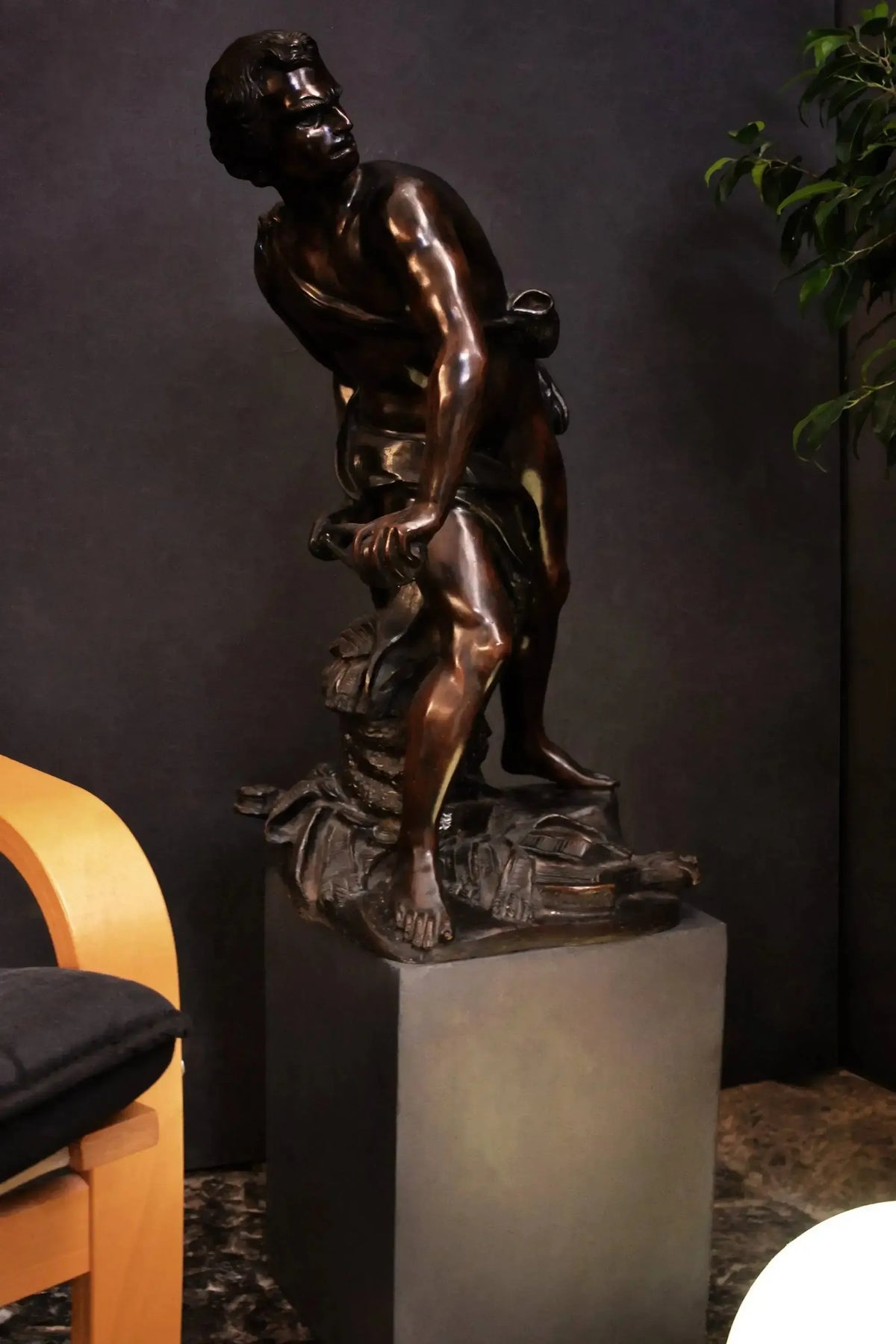 David di Bernini in bronzo brunito su un piedistallo, davanti a una parete scura e accanto a una poltrona.