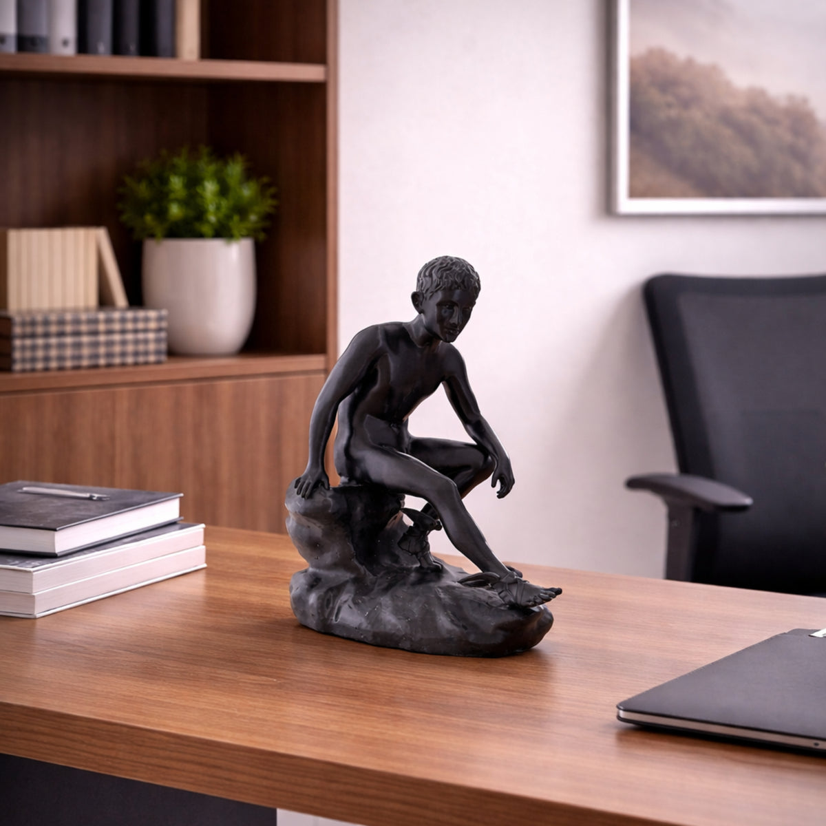 Hermes a riposo in PLA nero su una scrivania in legno accanto a libri e un portatile.