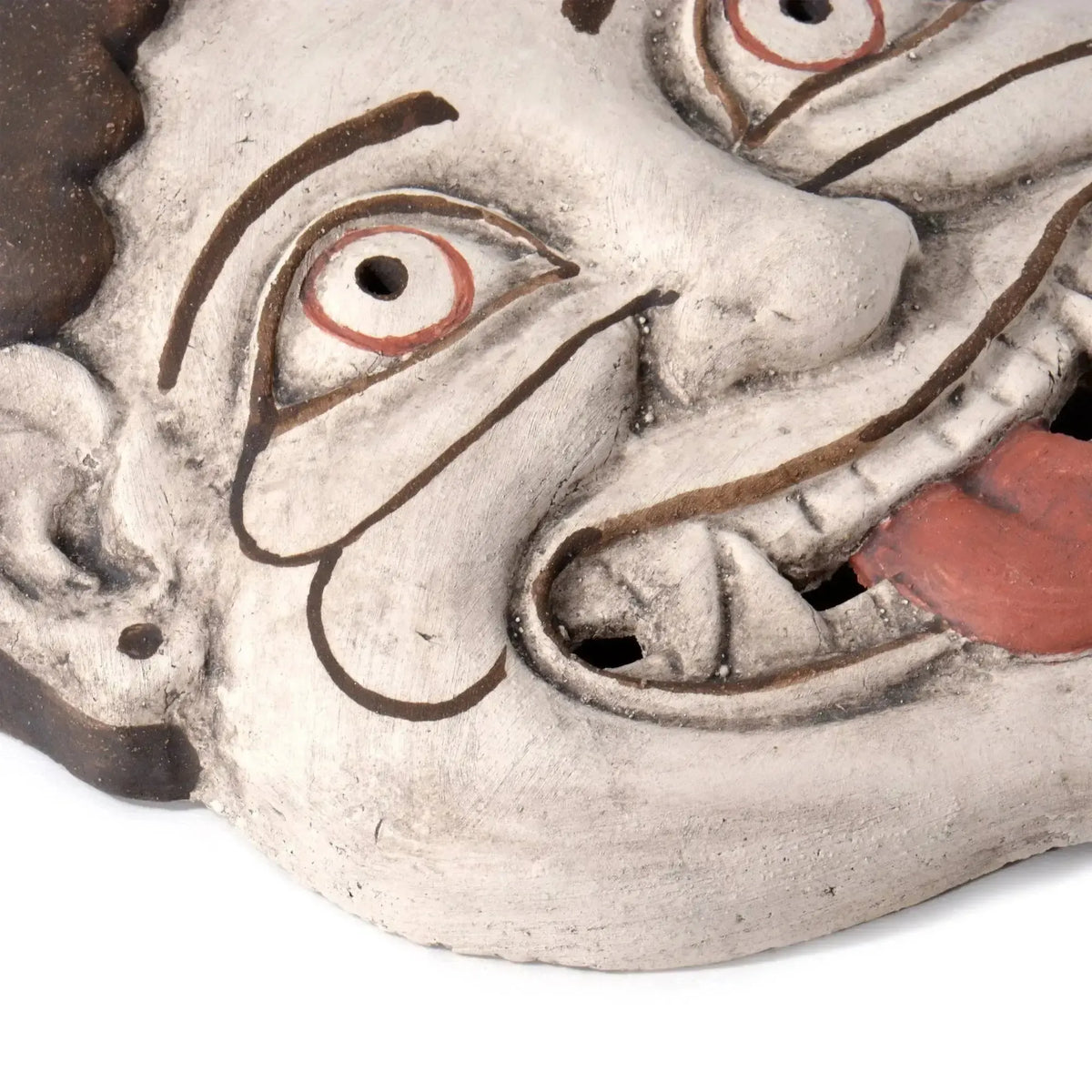 Dettaglio degli occhi, delle zanne e della lingua rossa della maschera Gorgone in terracotta