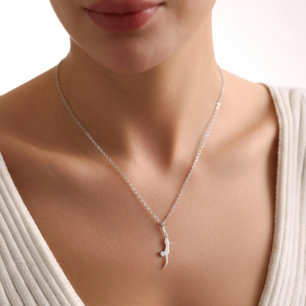 Pendente Tuffatore di Paestum piccolo in argento, indossato con una maglia chiara