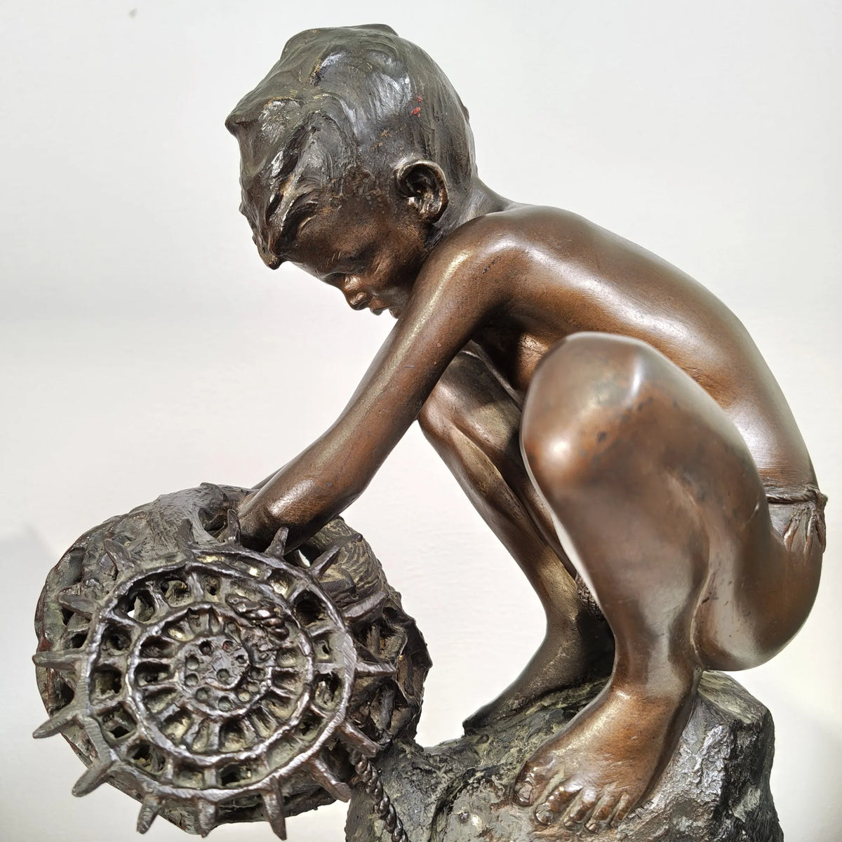 Dettaglio delle mani e della nassa nella scultura in bronzo