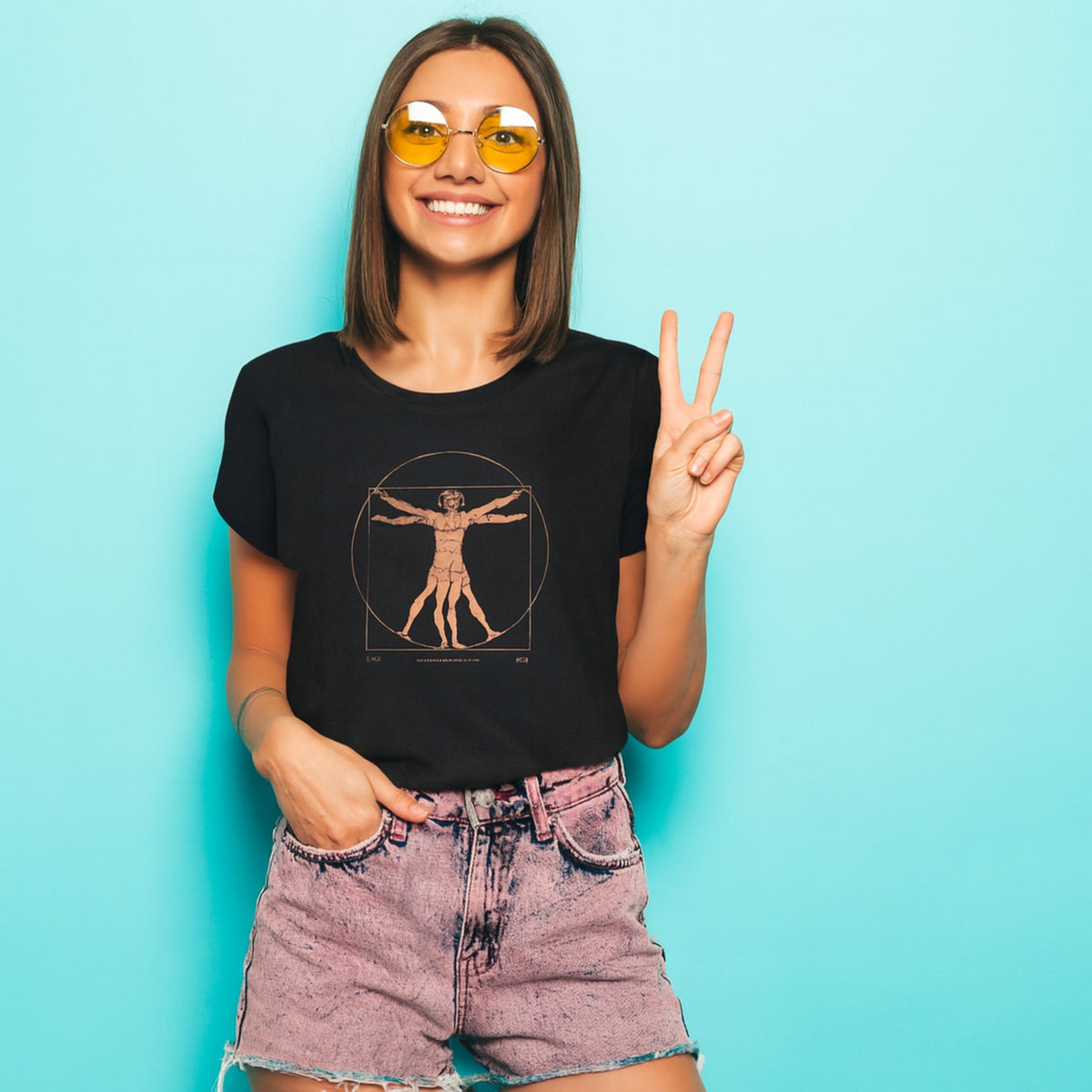 T-shirt donna nera con stampa dell’Uomo Vitruviano, indossata su sfondo turchese