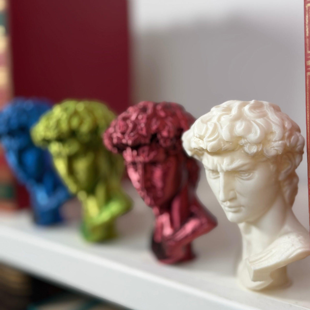 Testa del David in PLA bianco in primo piano, con altre tre riproduzioni colorate sfocate sullo sfondo.