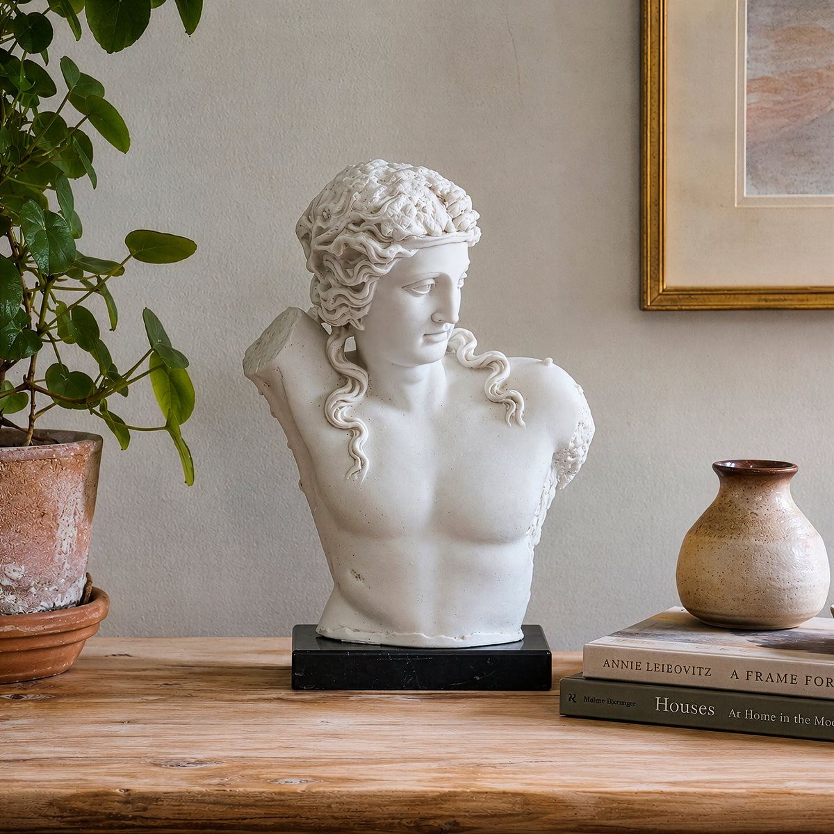 Torso di Dionisio in marmo su un tavolo in legno, accanto a libri e una pianta
