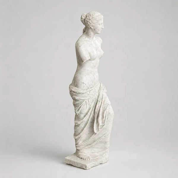 Venere di Milo in marmo di Carrara, vista di profilo su fondo grigio chiaro.