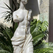 Statua della Venere di Milo in marmo posizionata elegantemente in un giardino.