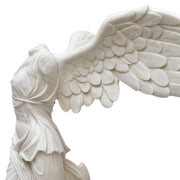 Vista ravvicinata laterale della statua in marmo della Vittoria Alata di Samotracia, con focus sui dettagli delle ali e dei drappeggi.
