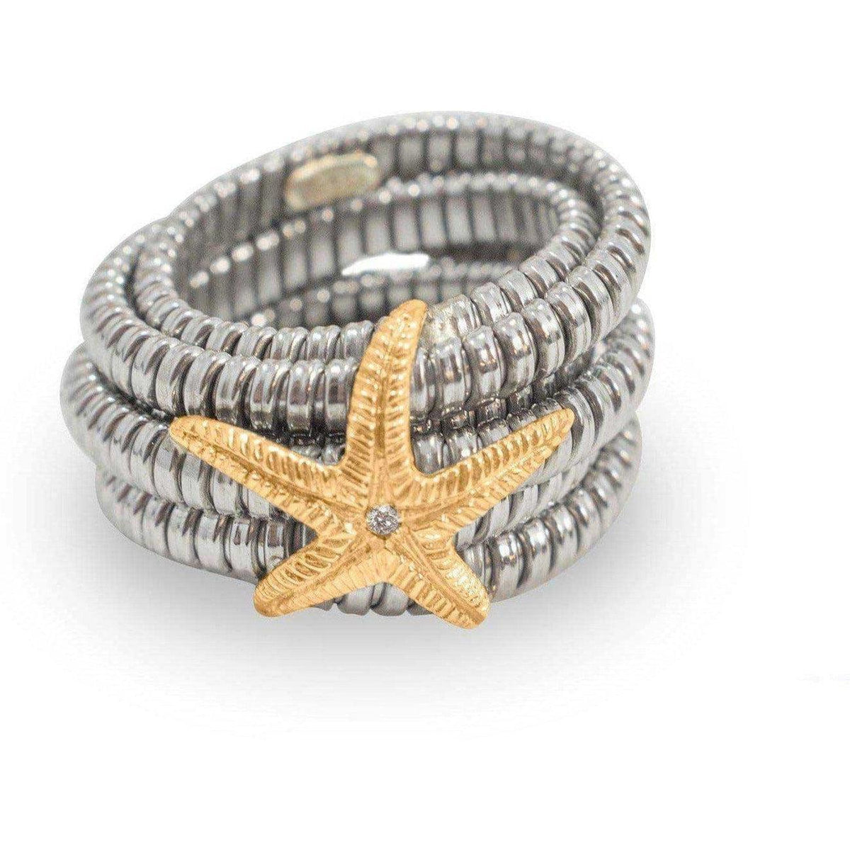Anello in acciaio con stella marina dorata e diamante centrale, visto in obliquo su fondo bianco