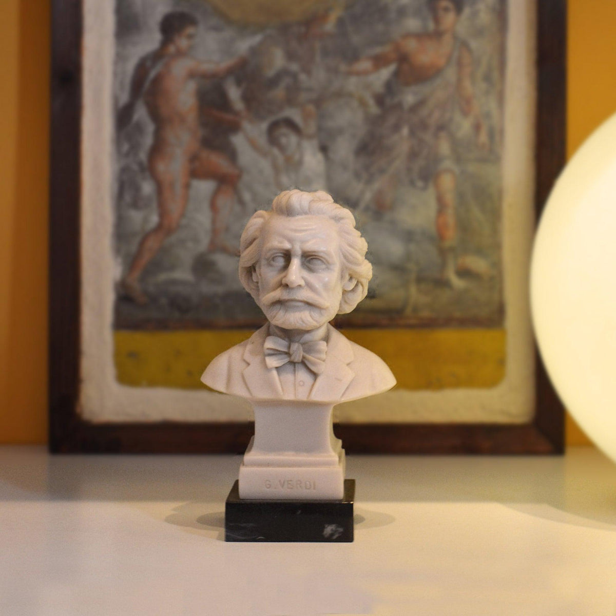 Busto di Giuseppe Verdi in marmo, davanti a un quadro e accanto a una lampada sferica