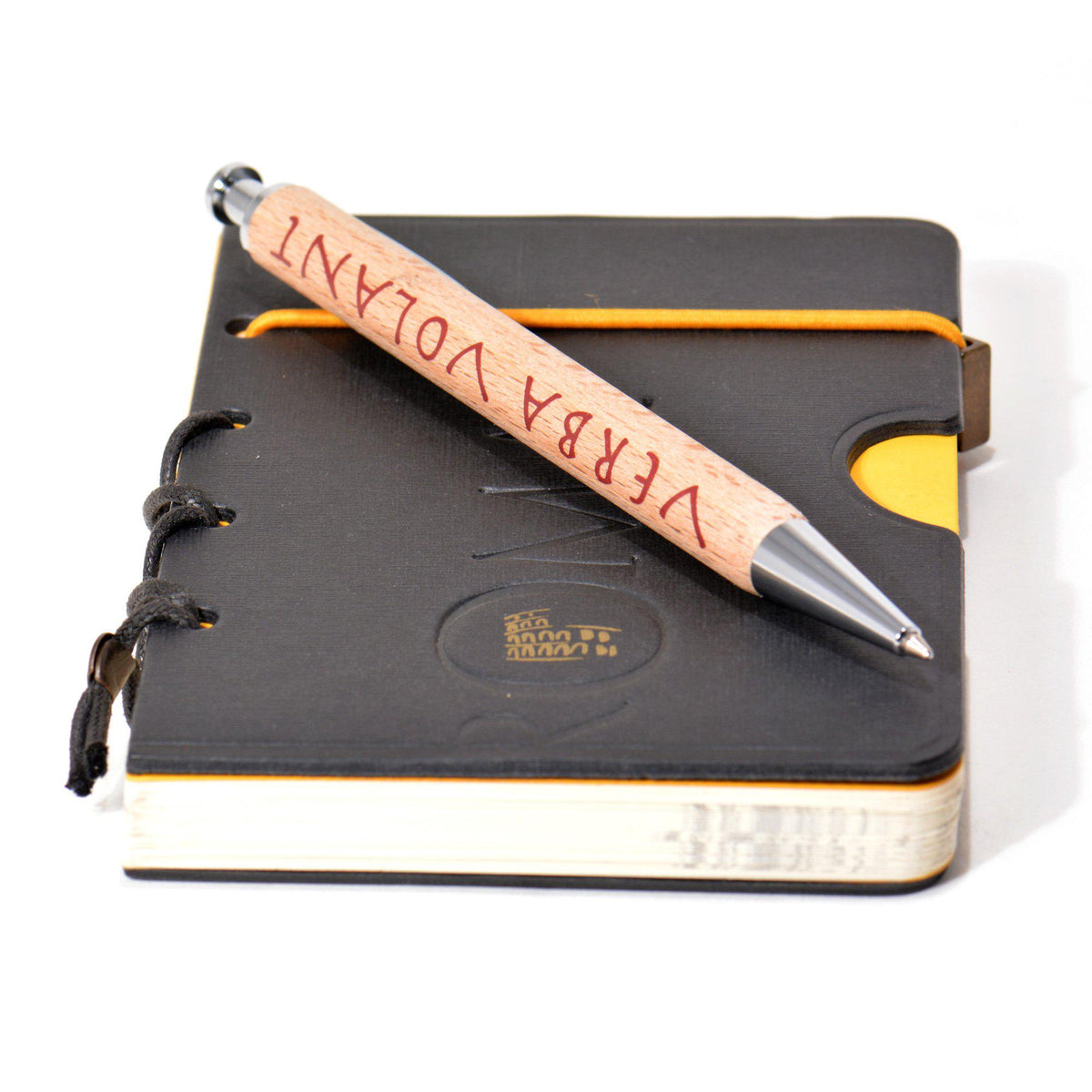 Penna Parker in legno con scritta «Verba Volant», posata su un taccuino nero Roma con elastico giallo.